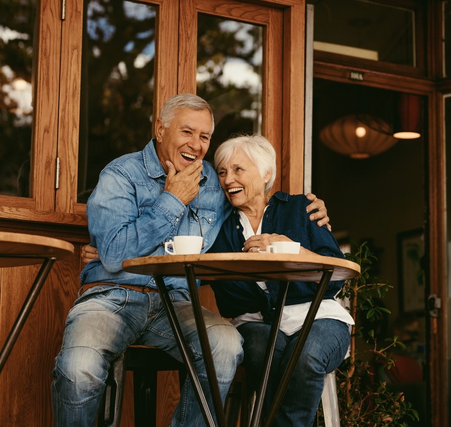 Senior couple sitting at a cafe patio smiling